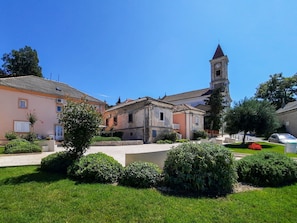 A courtyard with a church tower, surrounded by historic buildings and well-maintained greenery.