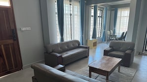 Uma sala de estar ampla com sofá, poltronas e mesa de centro.