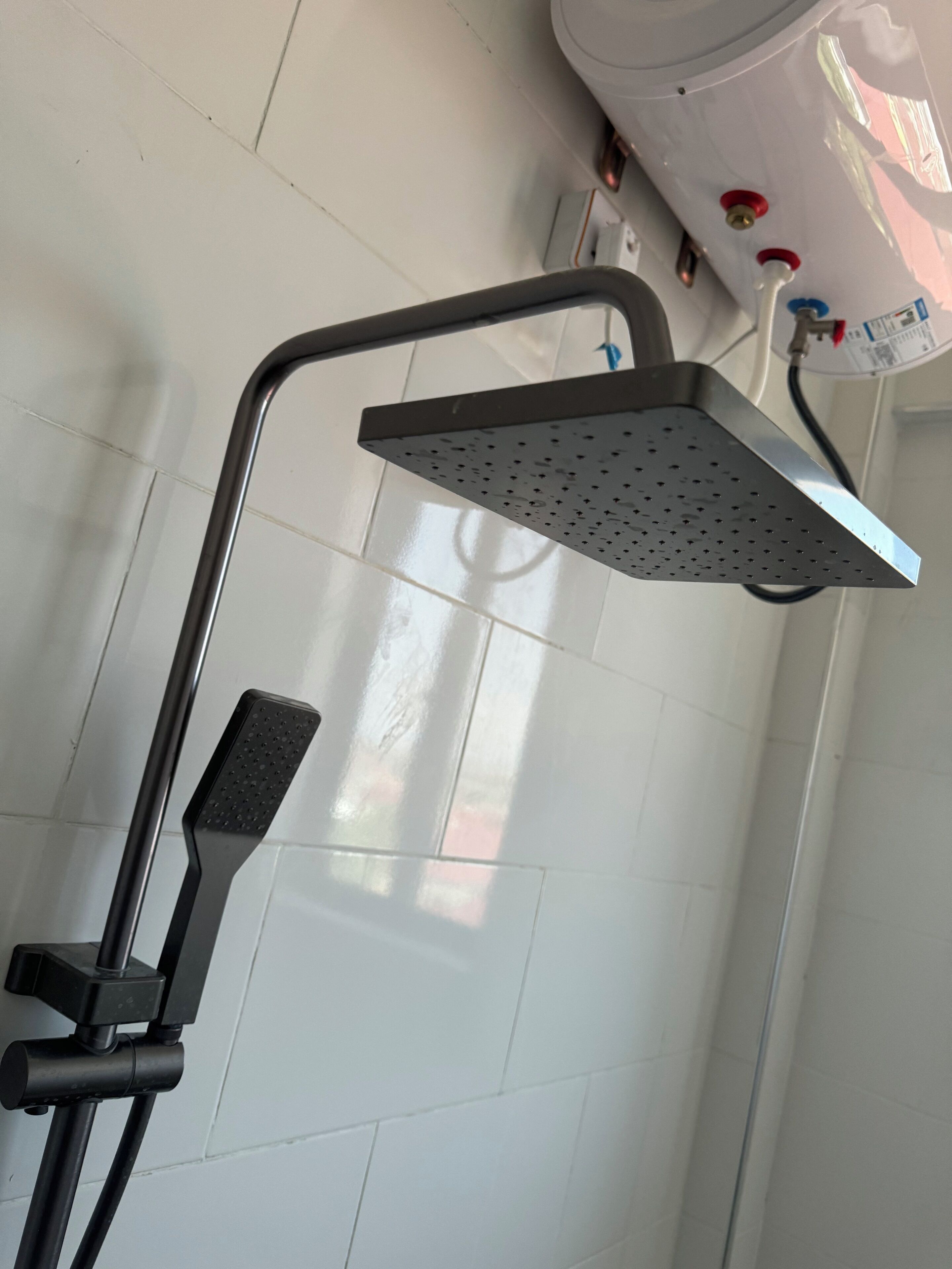 A shower with a handheld showerhead and a fixed overhead showerhead.