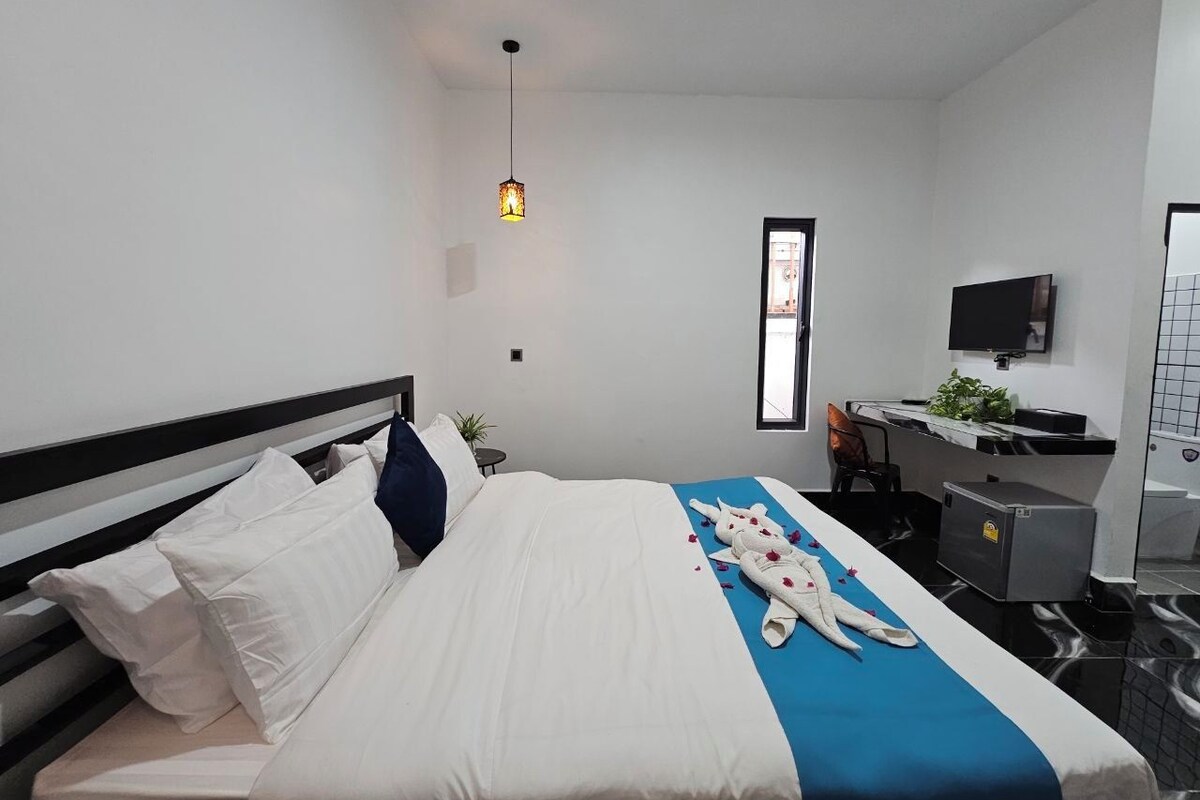 A hotel room with a bed, a desk, a chair, a television, and a bathroom.