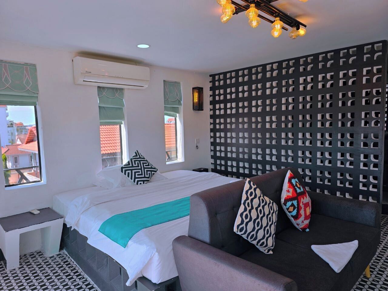 A hotel room with a bed, a sofa, a desk, and a decorative wall panel.