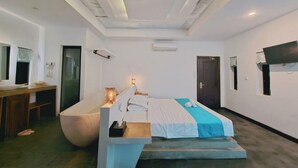A modern hotel room with a large bed, a built-in bathtub, a desk, and a TV mounted on the wall. - Angkor Rise Boutique (Siem Reap)