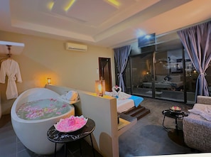 A modern hotel room with a large bathtub, a sofa, a small table, and a balcony with a view. - Angkor Rise Boutique (Siem Reap)