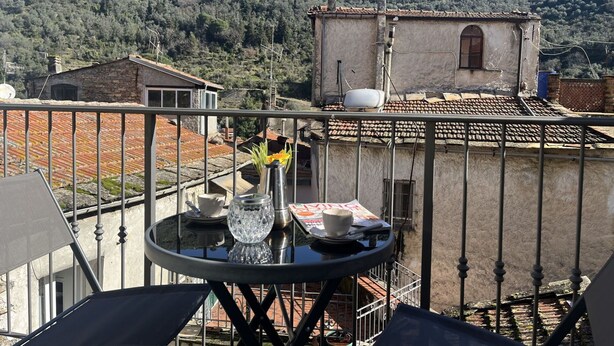 A balcony with a table, chairs, and a view of a hillside with buildings. - Beautiful private villa for 4 people with A/C, WIFI and terrace (Dolcedo)