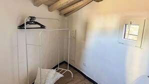 A small, clean room with a wooden ceiling, a metal drying rack, a white chair, and a small window. - Beautiful private villa for 4 people with A/C, WIFI and terrace (Dolcedo)