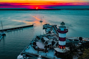 A waterfront property with a lighthouse, docked boats, and a pier extending into the water.