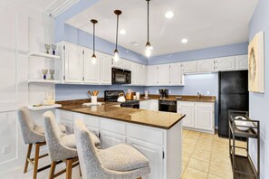 Una cocina moderna con armarios blancos, encimera de granito y refrigerador negro.