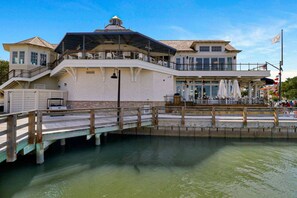 A waterfront property with a covered deck, a dining area, and a flag.