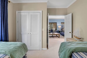 A hotel room with two beds, a closet, and a view into the living area.