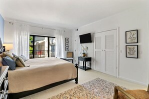A bedroom with a bed, a TV, a desk, and a chair.
