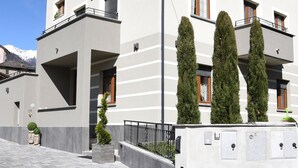 Een modern gebouw met twee verdiepingen, een balkon, een kleine tuin en een heldere lucht.
