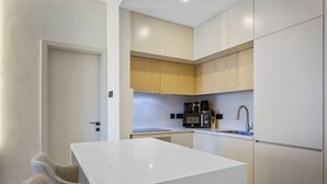 Una cocina compacta con armarios blancos, una encimera y un lavamanos.