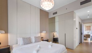 Une chambre d’hôtel moderne avec un grand lit, des tables de chevet, une armoire et un luminaire suspendu.