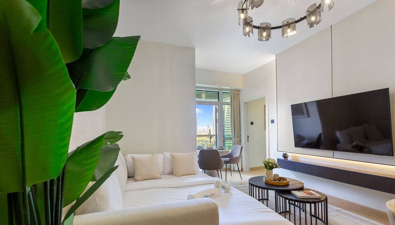 Un salon moderne avec un canapé, une table basse et un téléviseur à écran plat fixé au mur.