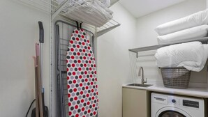 Un espace dédié à la lessive, comprenant un lave-linge, un étendoir et un panier.