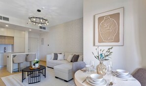 A modern living room with a dining area, a sofa, and a chandelier.
