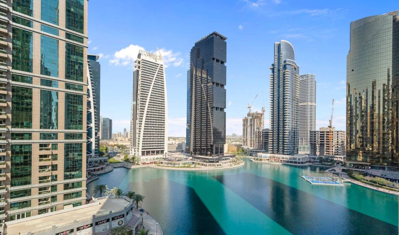 Une vue sur la ville, avec ses bâtiments modernes et imposants qui bordent le front de mer, un port de plaisance et un ciel dégagé.