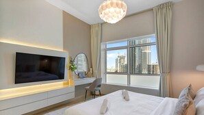 Habitación de hotel moderna con una cama grande, televisor de pantalla plana, escritorio con silla y un amplio ventanal con vistas a la ciudad.