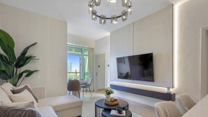 Un salon moderne avec un téléviseur à écran plat fixé au mur, un canapé, une table basse et une plante en pot.