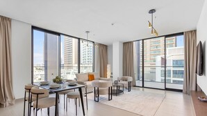 Een moderne woonkamer met een eethoek, grote ramen en uitzicht op de stad.