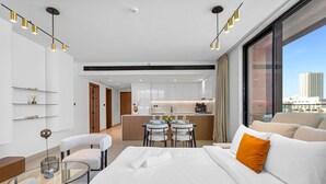 Een moderne hotelkamer met een bed, een zithoek, een eethoek en uitzicht over de stad.