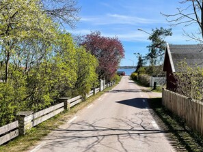 A rural road flanked by wooden fences and trees, leading towards a body of water. - 4 Star Holiday Home in Karlskrona (Hasslö)