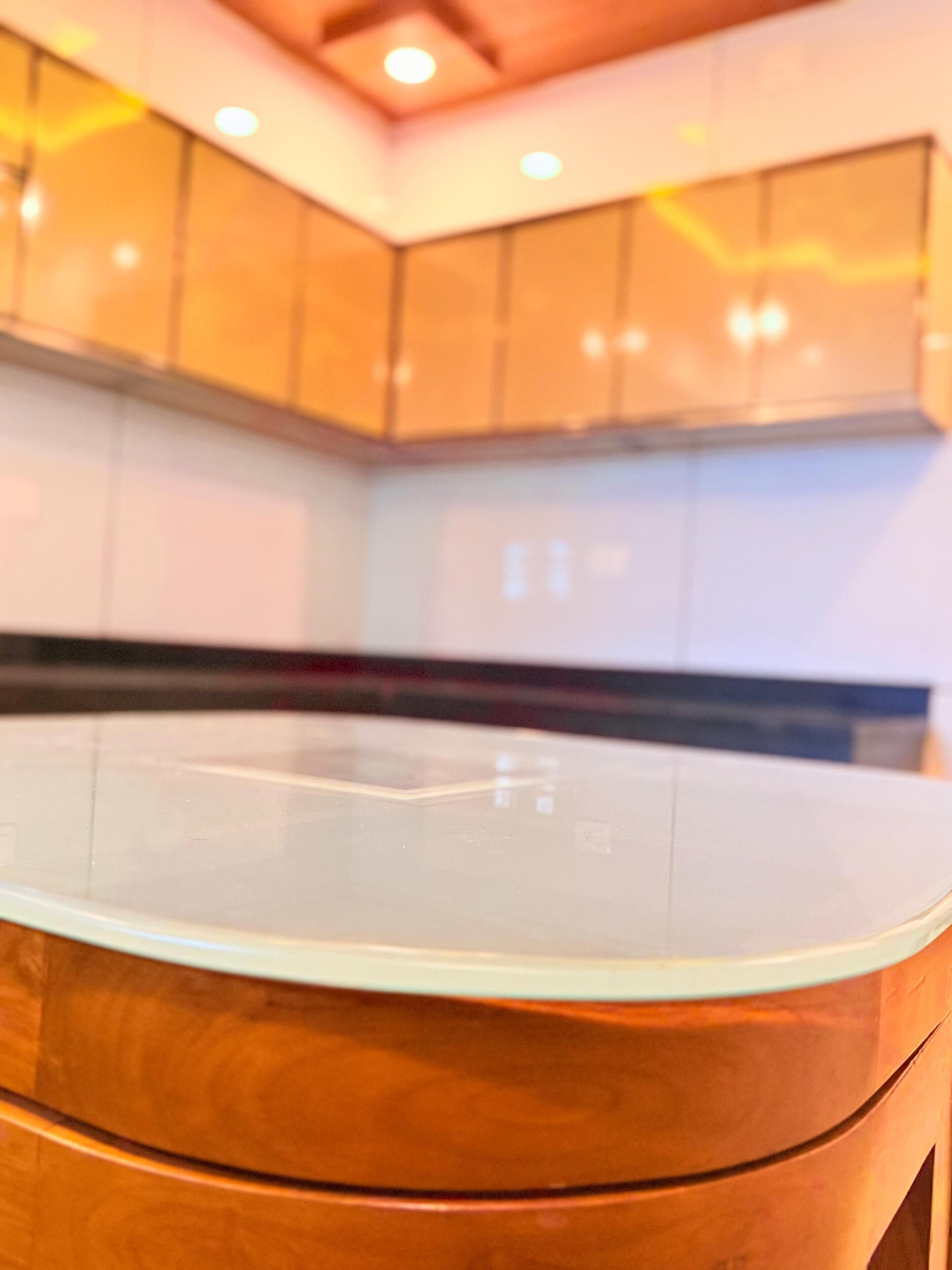 Una cocina moderna con una isla central, armarios de madera e iluminación empotrada en el techo.