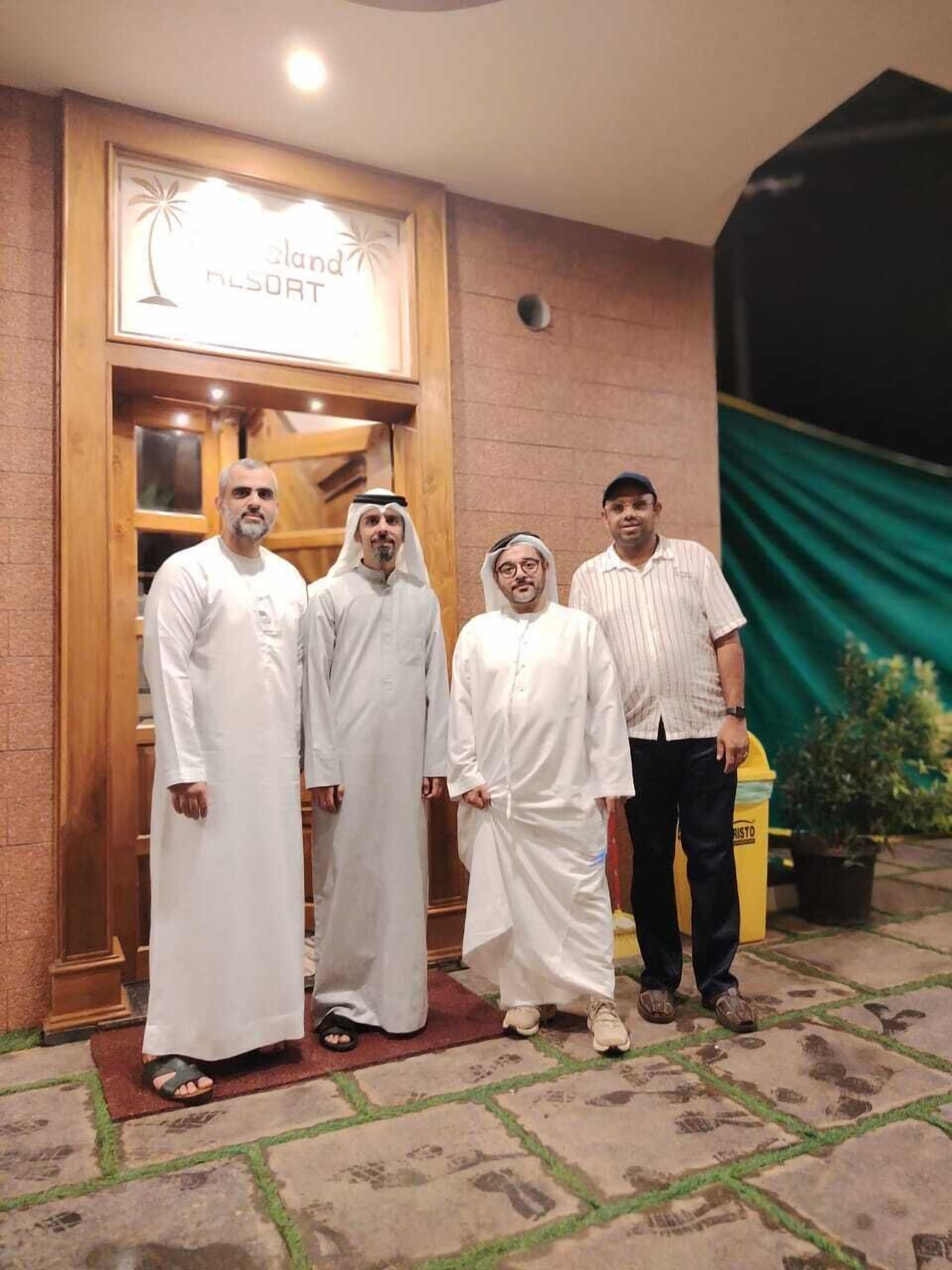 A group of four men standing in front of a building with a sign that reads "land resort".