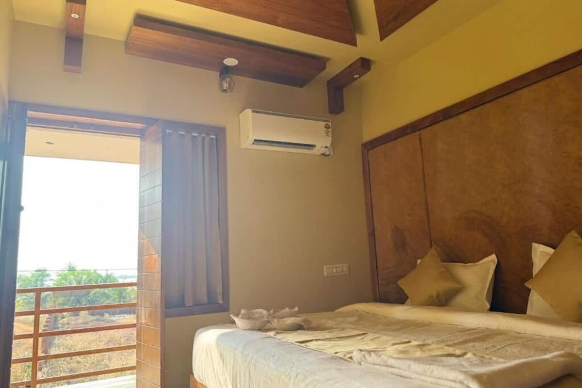 Un dormitorio con cama, vigas de madera en el techo, una ventana con cortinas y un equipo de aire acondicionado.