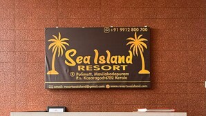 Balcão de recepção com placa do Sea Island Resort, incluindo informações de contato e detalhes de localização.