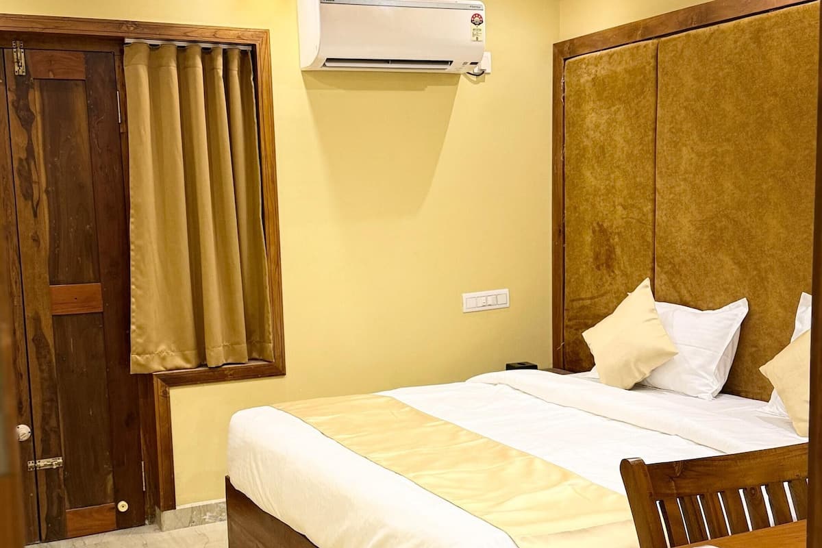 Un dormitorio con una cama de madera, una mesita de noche, un escritorio, un ventilador de techo y un aire acondicionado.