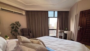 Una habitación de hotel con una cama grande, una silla, un escritorio y vistas a la ciudad desde la ventana.