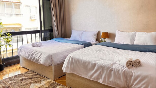 Habitación de hotel con dos camas, un balcón y vistas al exterior.