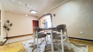 A dining area with a table and four chairs, a patterned rug, and a wooden floor.