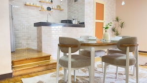 Una cocina moderna con paredes de ladrillo blanco, estantes de madera y una zona de comedor con una mesa redonda y cuatro sillas.