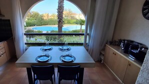 Una cocina con una mesa de comedor para dos, vista a una piscina y un reloj en la pared.