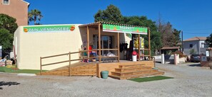 Un pequeño mercado con estructura de madera, una rampa y un letrero que dice 'Pain-Viennoiserie'.