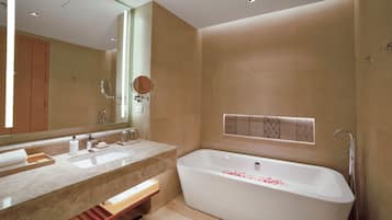 A modern bathroom with a large bathtub, two sinks, and a mirror.