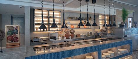 A modern kitchen with a central island, hanging pendant lights, and a tiled backsplash.