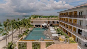 A resort with a pool, palm trees, and a view of the sea.