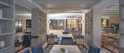 A spacious dining area with a long table, blue upholstered chairs, and a central island with seating.