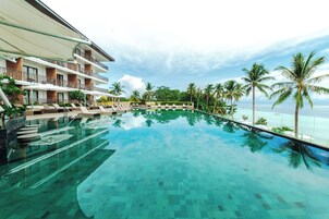 A hotel pool with clear water, lounge chairs, and palm trees.