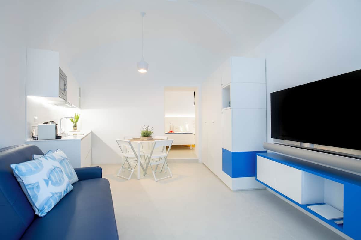 A modern living room with a sofa, TV, and dining area.