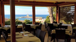 An outdoor dining area with tables and chairs, overlooking a coastal view with a lighthouse. - Al Castello Relais (Vieste)