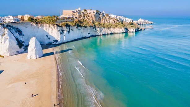 A coastal town with white cliffs, a sandy beach, and a clear blue sea. - Al Castello Relais (Vieste)