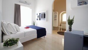A modern hotel room with a bed, a desk, a TV, and a potted plant. - Al Castello Relais (Vieste)
