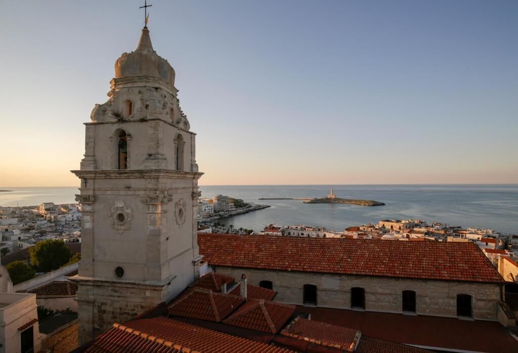 A historic building with a prominent tower and a view of the sea.