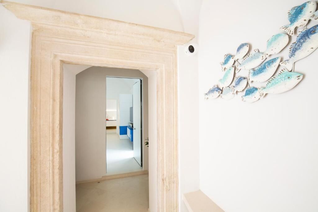 Un pasillo con un espejo que refleja una habitación con armarios azules.