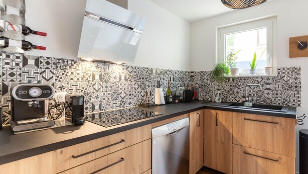 Una cocina moderna con baldosas estampadas, horno empotrado y ventana con vistas.