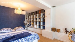 Un dormitorio con cama, estantería empotrada, candelabro y aire acondicionado instalado en la pared.
